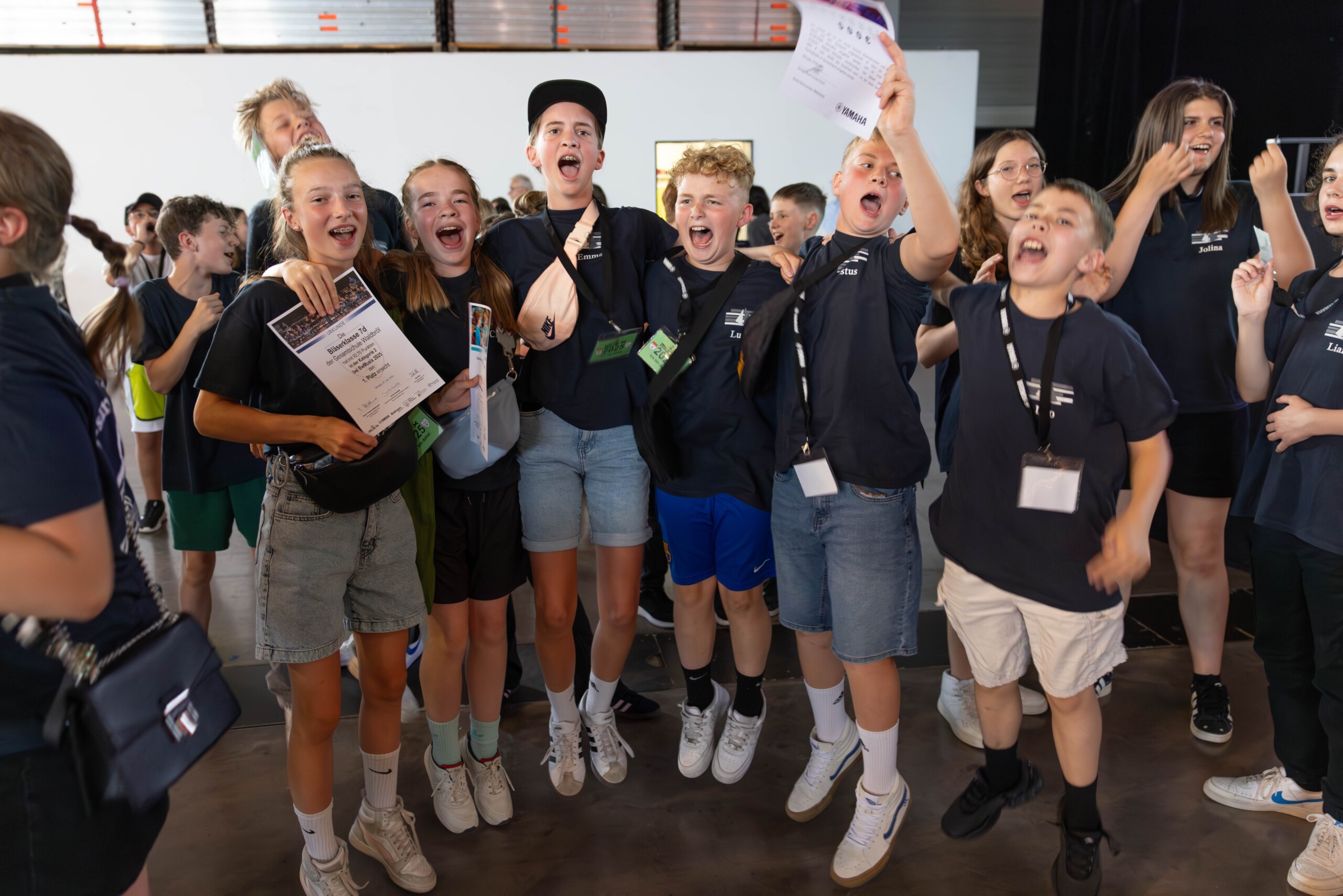 Jubelnde Schüler:innen der Bläserklasse 7d direkt nach der Siegerehrung – mit Urkunden in den Händen und breitem Lachen im Gesicht feiern sie ihren ersten Platz beim BW Musix-Wettbewerb.