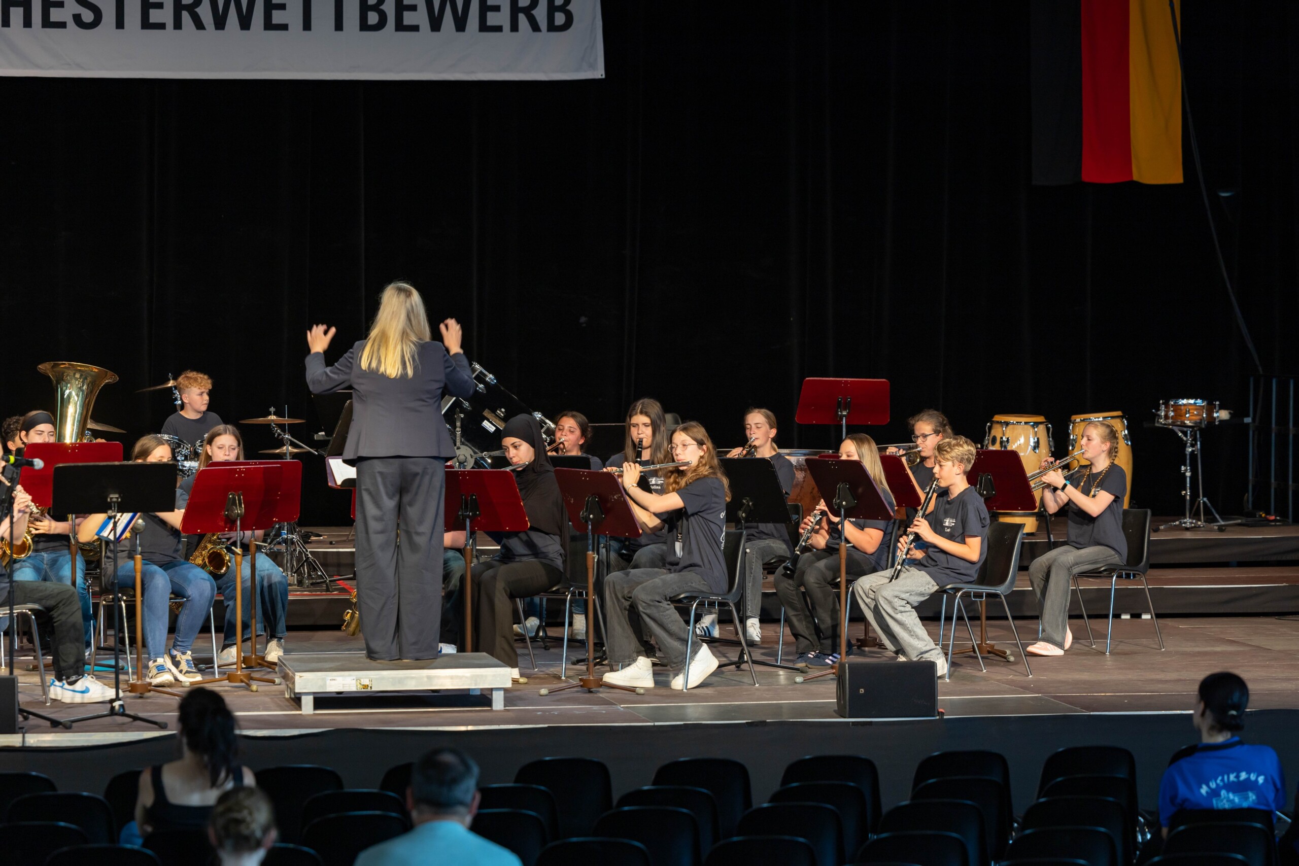 Auftritt der Bläserklasse 7d auf der großen Bühne der Volksbankmesse – unter der Leitung von Christine Jahn spielt das Ensemble konzentriert und geschlossen vor Publikum.
