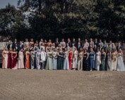 Gruppenfoto des Abiturjahrgangs 2025 der Gesamtschule Waldbröl auf dem Schulhof – die Abiturient:innen stehen festlich gekleidet in mehreren Reihen vor einer grünen Baumkulisse und lächeln in die Kamera.