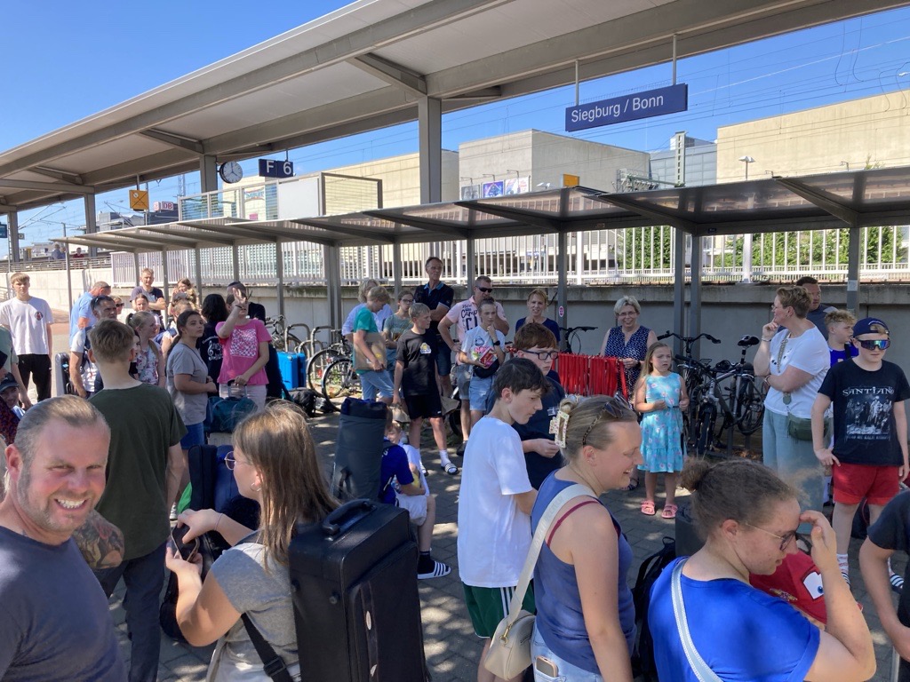 Abfahrt vom Bahnhof Siegburg: Schüler:innen der Bläserklasse 7d und ihre Familien versammeln sich auf dem Bahnsteig – Instrumente, Koffer und gespannte Vorfreude auf ein musikalisches Wochenende in Balingen.