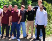 Gruppenfoto beider Teams der Gesamtschule Waldbröl vor grüner Kulisse im Schlosspark Eller: Die Jugendlichen stehen entspannt nebeneinander, einige mit verschränkten Armen, andere mit lachendem Blick zur Kamera.