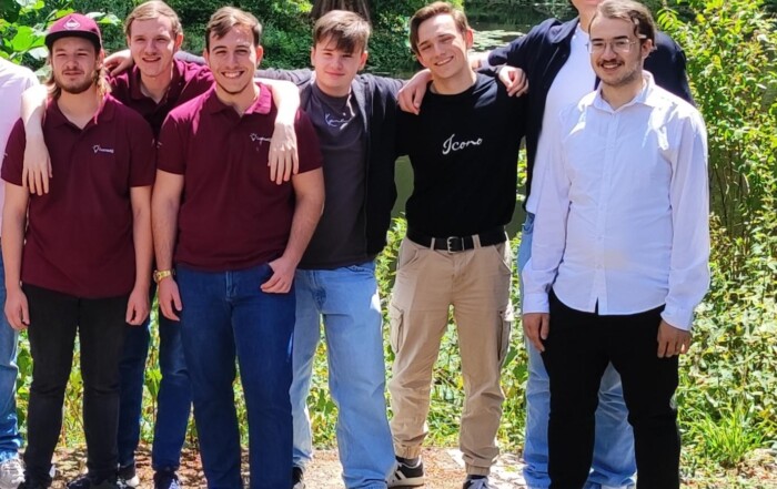Gruppenfoto beider Teams der Gesamtschule Waldbröl vor grüner Kulisse im Schlosspark Eller: Die Jugendlichen stehen entspannt nebeneinander, einige mit verschränkten Armen, andere mit lachendem Blick zur Kamera.