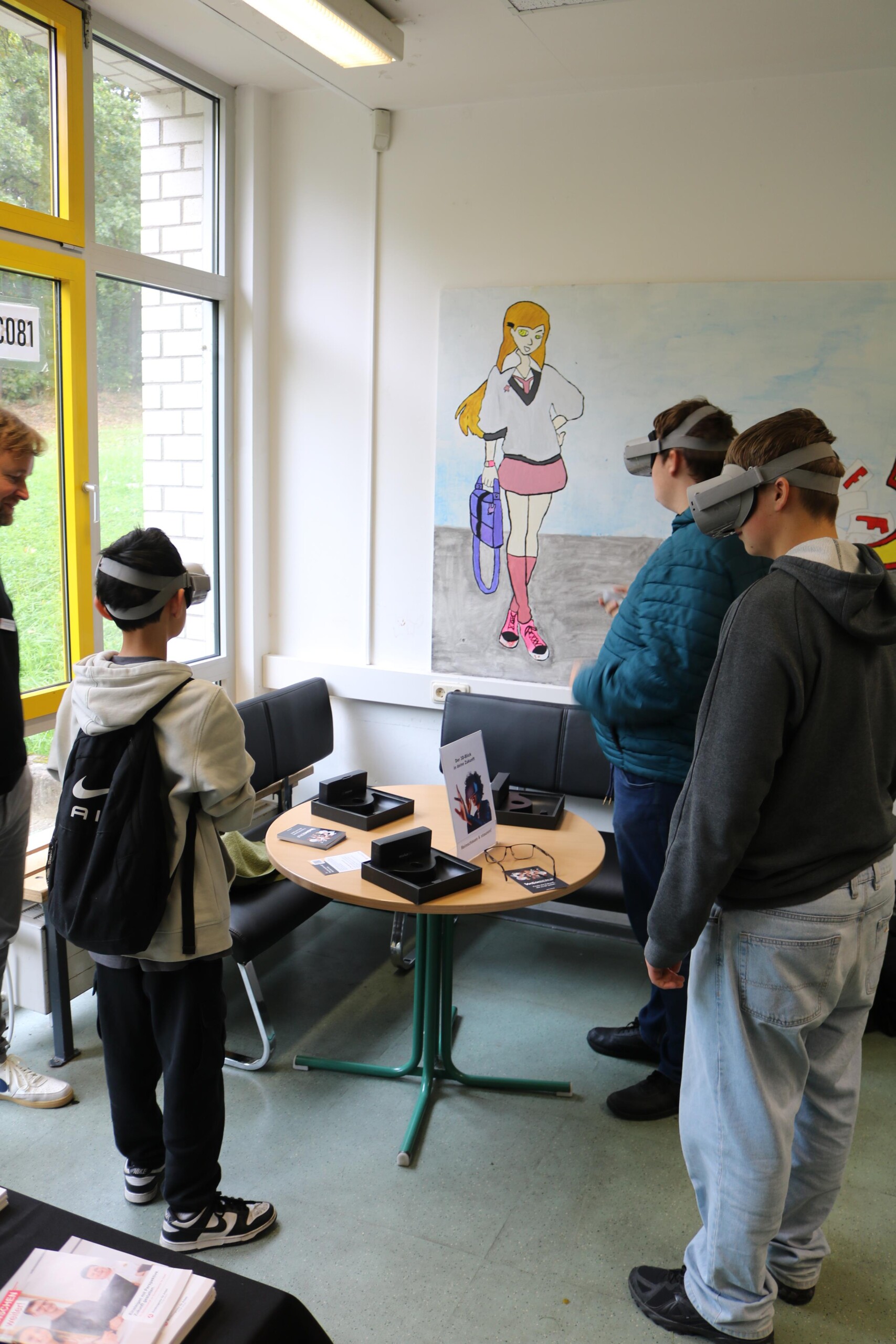 Vier Jungen tragen Virtual-Reality-Brillen und probieren eine digitale Simulation aus. Ein Erwachsener begleitet die Szene.