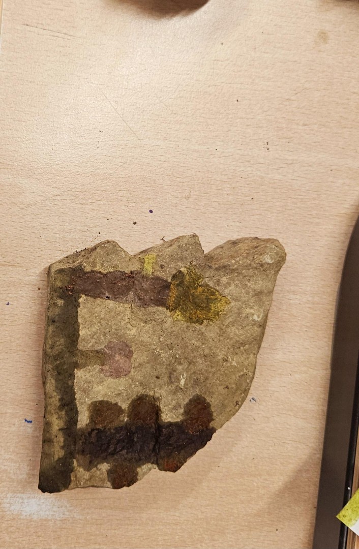 Ein bemalter Stein zeigt verschiedene erdfarbene Muster aus dem Höhlenmalerei-Workshop.