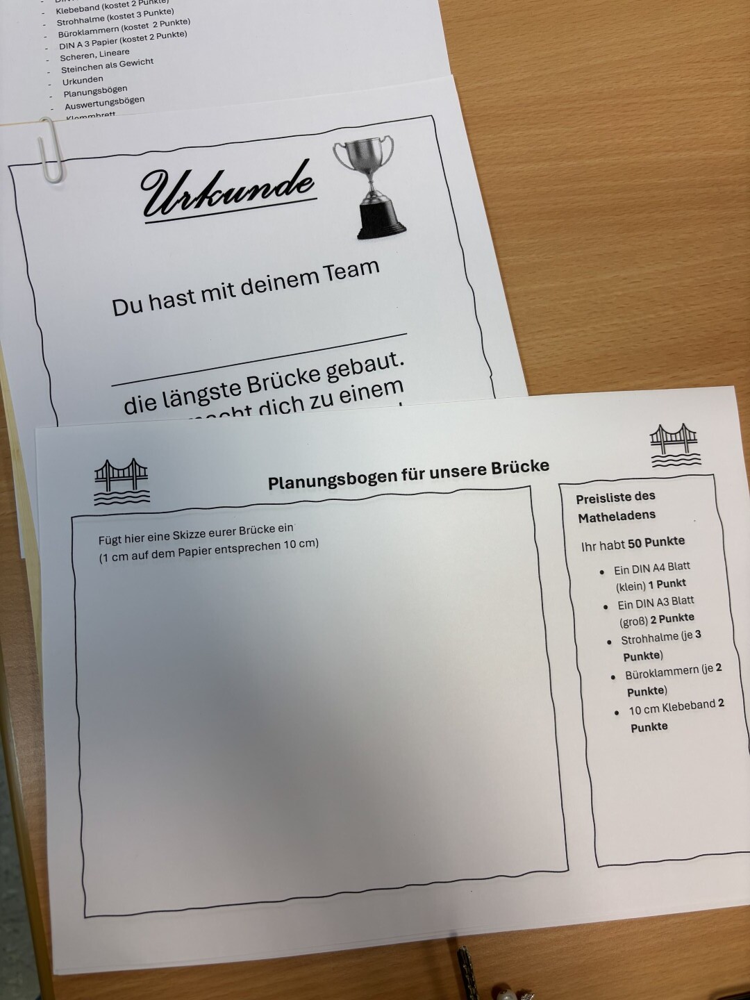 Eine Urkunde und ein Planungsbogen für ein Brückenbau-Projekt liegen nebeneinander auf einem Tisch.