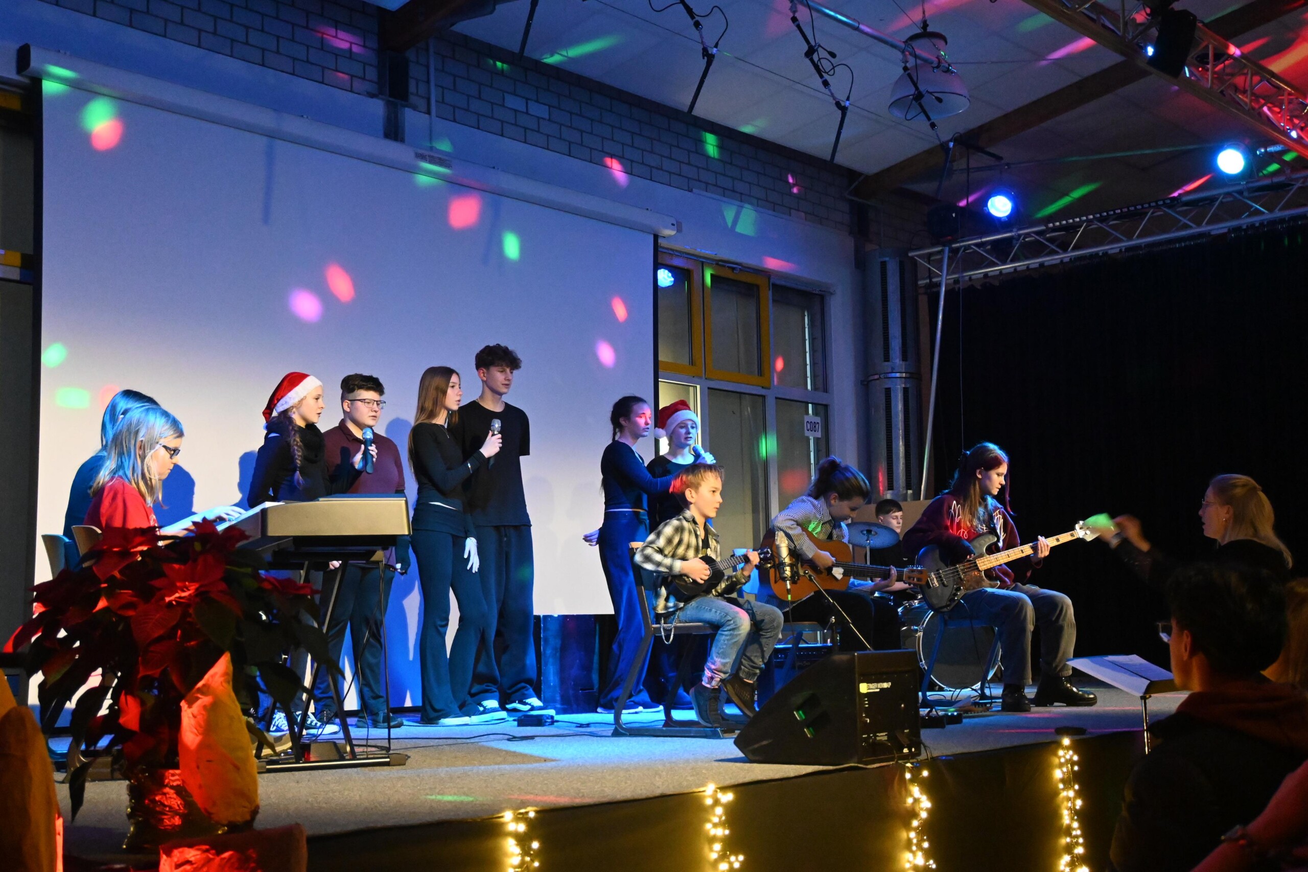 Band-AG der Gesamtschule mit Schüler:innen an Gitarren, Bass, Schlagzeug und Keyboard sowie mehreren Sänger:innen auf der Bühne bei einem Auftritt während „Lichter im Advent“.