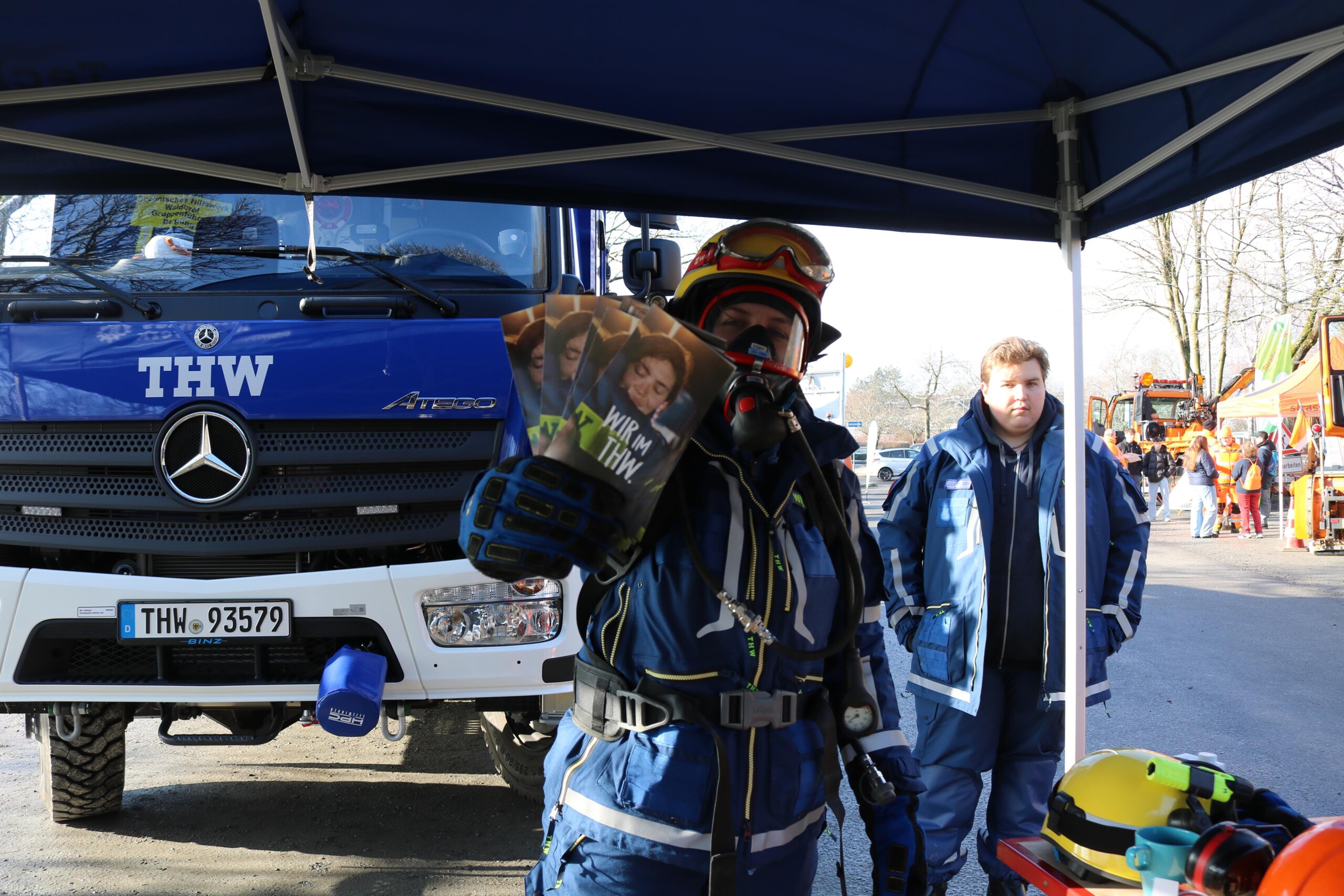 Ein Mitglied des Technischen Hilfswerks demonstriert Schutzkleidung und Ausrüstung im Außenbereich. Die Präsentation verbindet Information mit anschaulicher Demonstration.