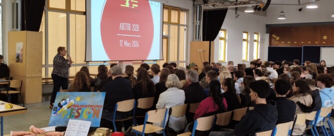 Volle Mensa beim Infoabend: Schüler:innen und Eltern verfolgen die Einführung zur Kurswahl vor einer Präsentation.