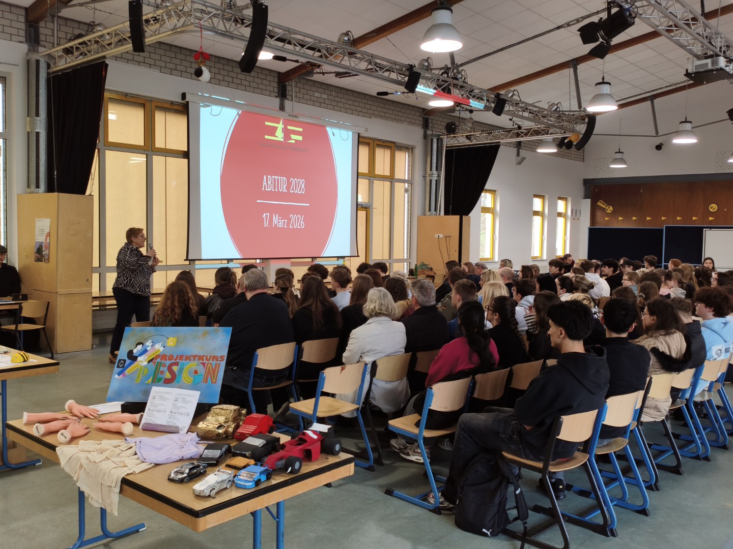 Volle Mensa beim Infoabend: Schüler:innen und Eltern verfolgen die Einführung zur Kurswahl vor einer Präsentation.