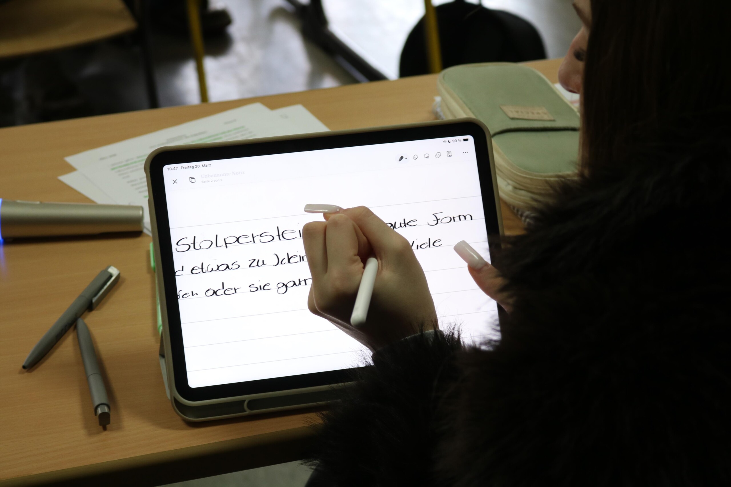Schülerin schreibt auf einem Tablet einen Text über Stolpersteine und deren Bedeutung im Rahmen des Projekttags.