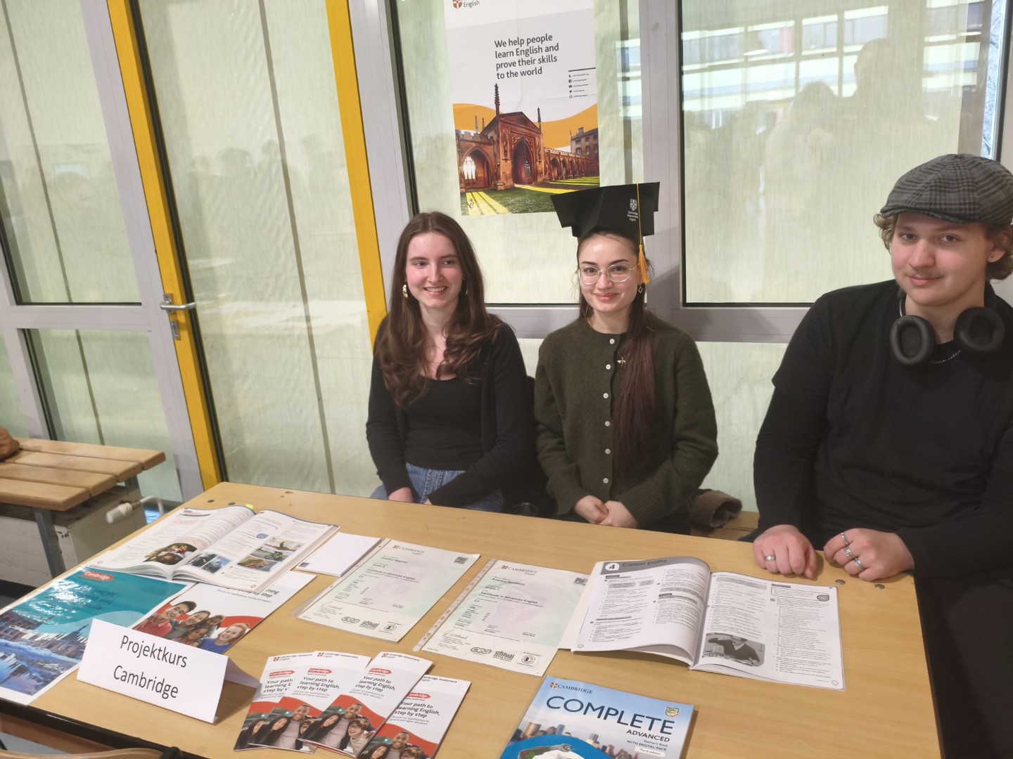 Schüler:innen informieren am Stand über den Projektkurs „Cambridge“ und zeigen Materialien und Zertifikate.