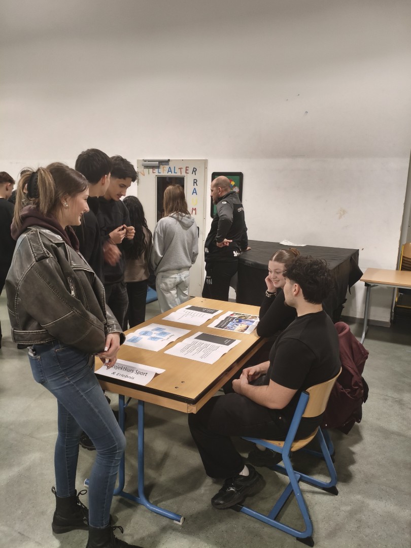 Beratungssituation am Stand „Sport“: Schüler:innen der Q1 erklären Inhalte im direkten Gespräch mit Interessierten.