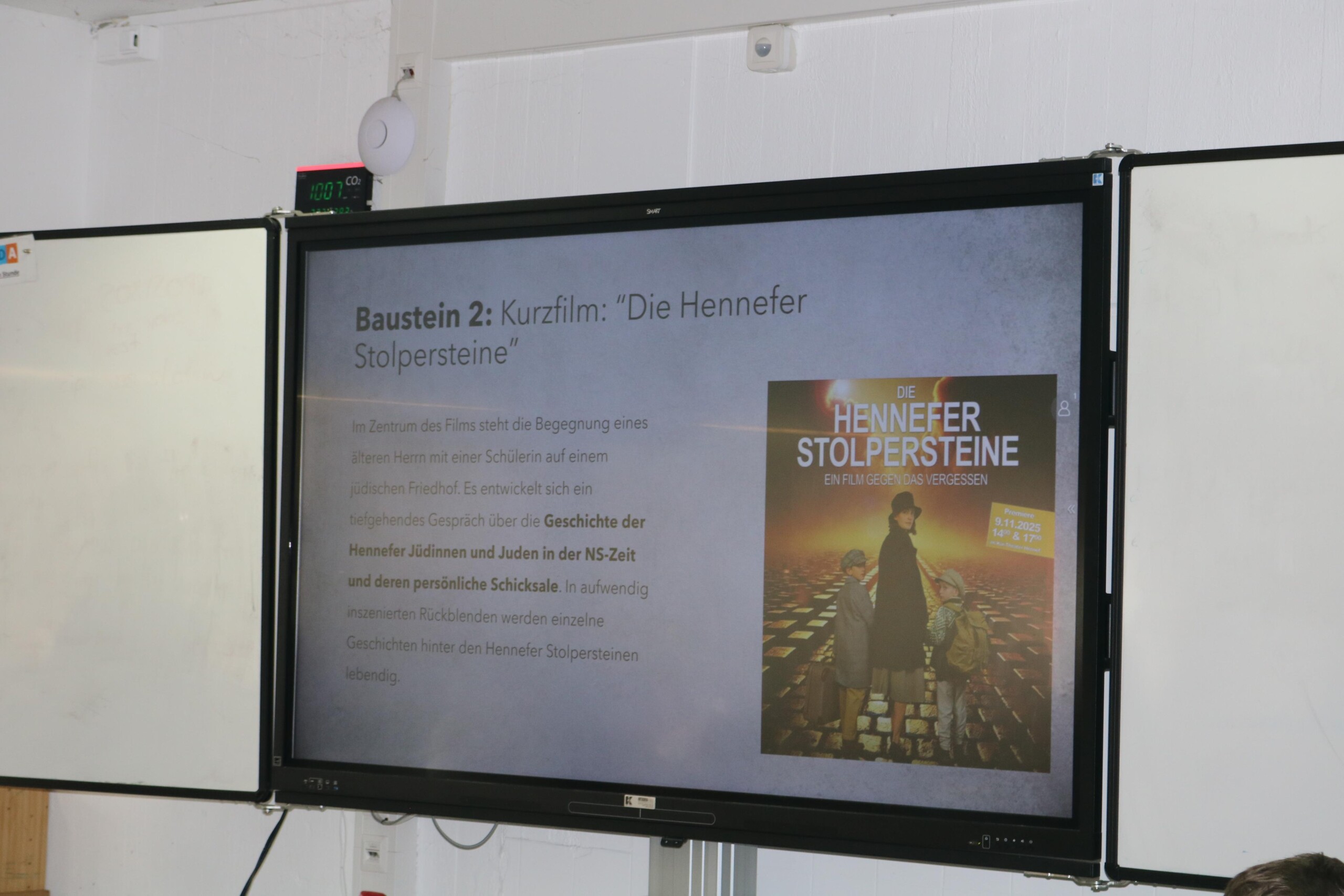 Tafelbild mit Informationen zum Kurzfilm „Die Hennefer Stolpersteine“ wird im Unterricht auf einem Bildschirm gezeigt.