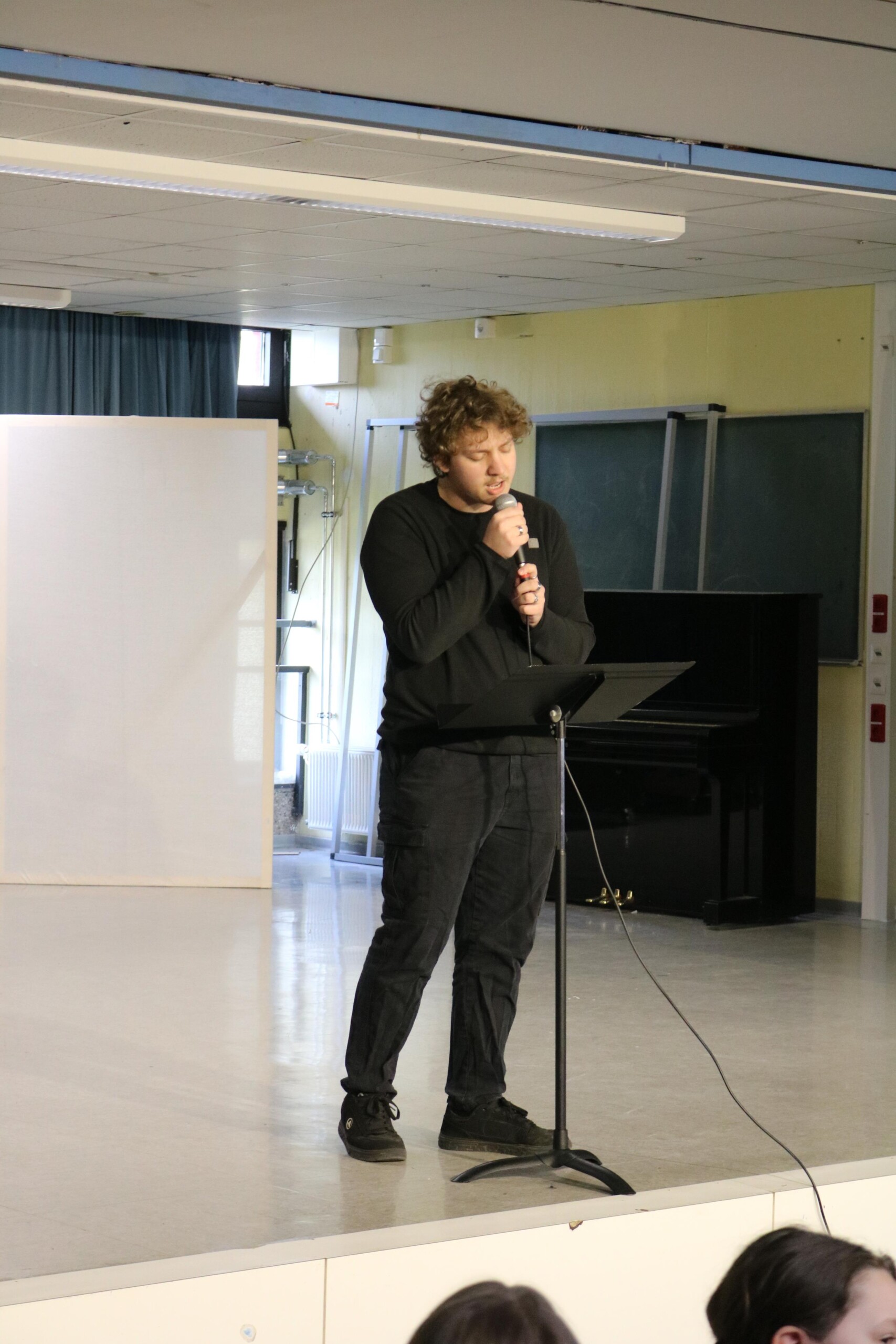 Finn Kalsner steht mit Mikrofon am Notenständer und singt seinen Beitrag bei der Open Stage.